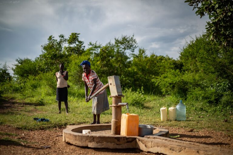 Awuru beim pumpen von Wasser eines neuen Brunnens in Uganda. Brunnenbau.